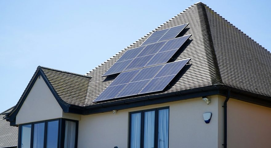 A tiled house roof with a solar array laid out across the sunlit south-facing plane